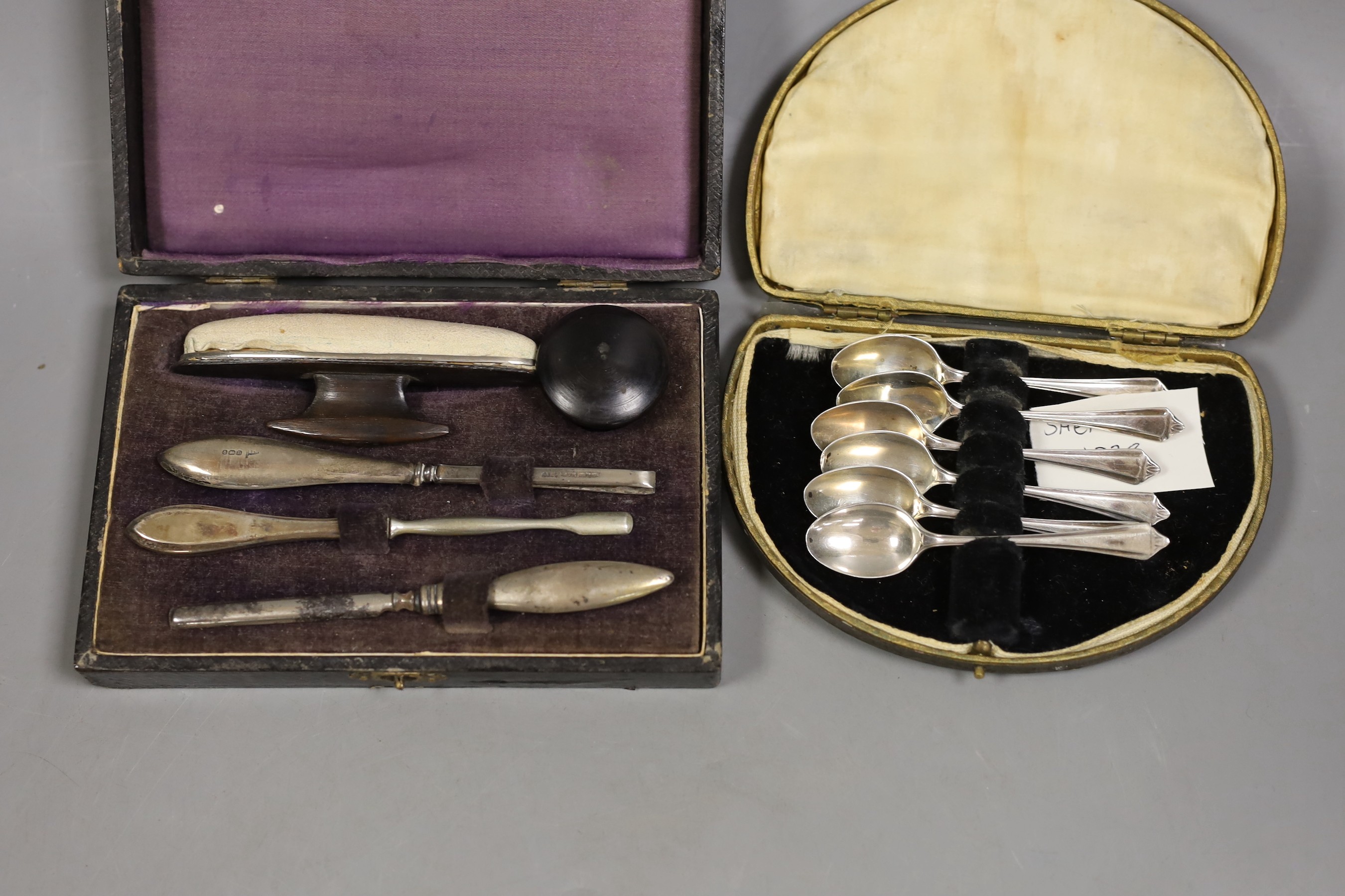 A cased set of six white metal and enamel cocktail sticks and three other cased sets including silver tea and coffee spoons and a manicure set.